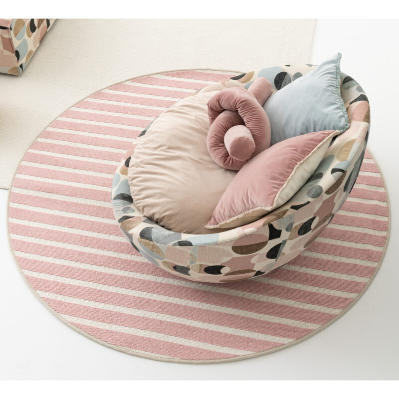 Contemporary cozy armchair with patterned fabric and plush pillows on a striped pink rug by LEOPARD Furniture, Canada.