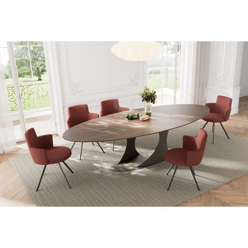 Luxurious oval dining table avec fauteuils rouges dans un intérieur moderne et raffiné par LEOPARD Furniture, Canada.