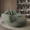 Green curved sectional sofa in a cozy modern living room with wooden wall and bookshelf. LEOPARD Furniture elegant design.